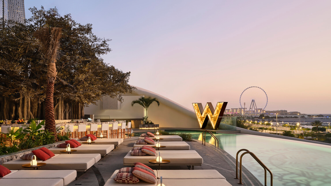 A terrace with elegant beach loungers and a swimming pool over looking Dubai&amp;#039;s skyline at sunset