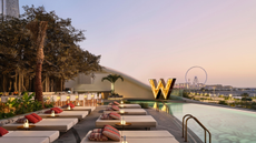 A terrace with elegant beach loungers and a swimming pool over looking Dubai's skyline at sunset