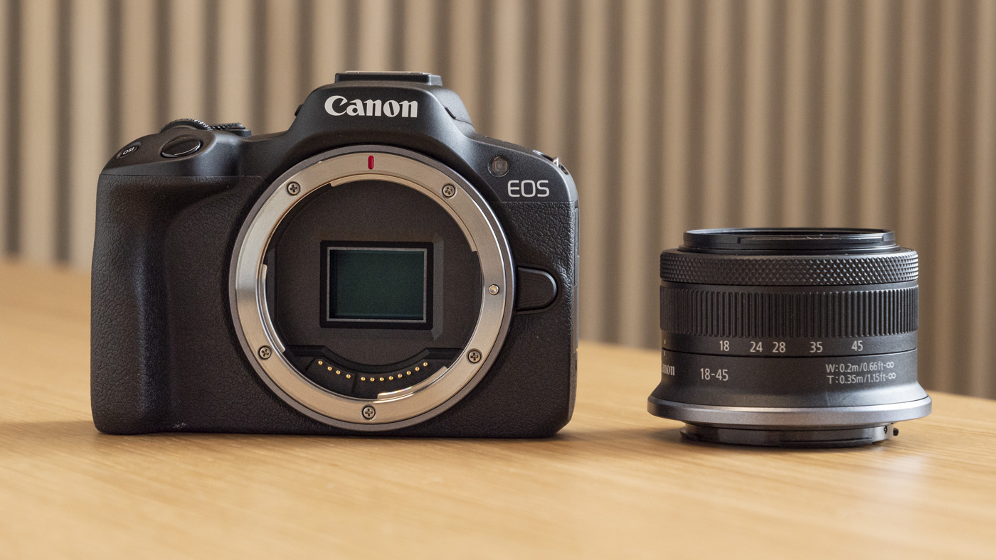 Canon EOS R50 on a table with 18-45mm lens next to it