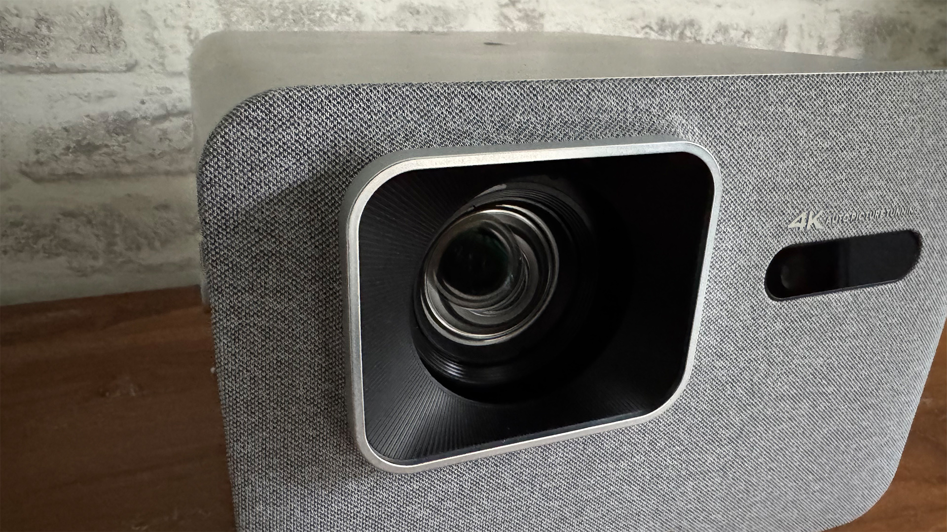 BenQ TK705i home cinema projector on wooden sideboard in front of white brick wall