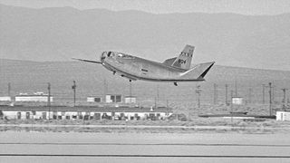 a black and white image of an experimental aircraft as it approaches its first landing on a desert runway