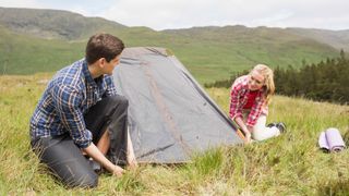 how to pitch a tent: couple setting up wild camp