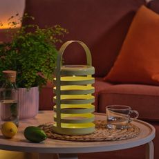 IKEA's SOLVINDEN solar outdoor lantern lit up on a garden coffee table in the dark