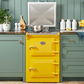 Yellow Everhot range cooker in a kitchen with green cabinets and green backsplash