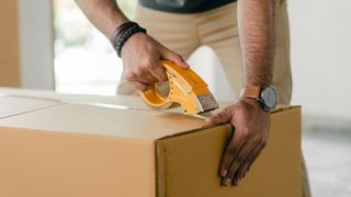 Man taping up packing box to return a mattress to Amazon