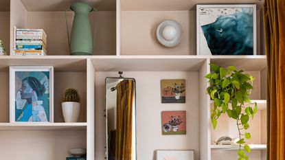 Pink built-in shelving until with artwork, books, plants and vases