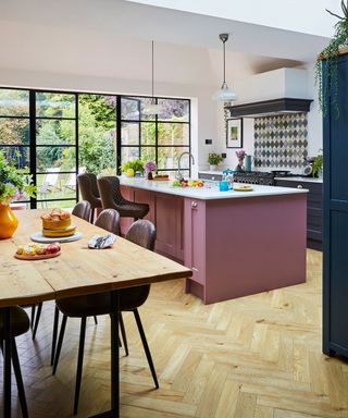 pink kitchen island in kitchen diner with black critall style doors and windows to garden area