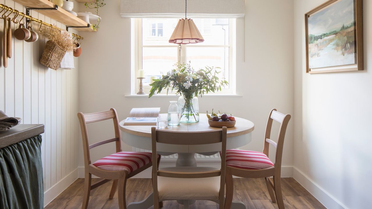 an open plan kitchen diner with a blue/green cabinet skirt, open shelving and a dining table 