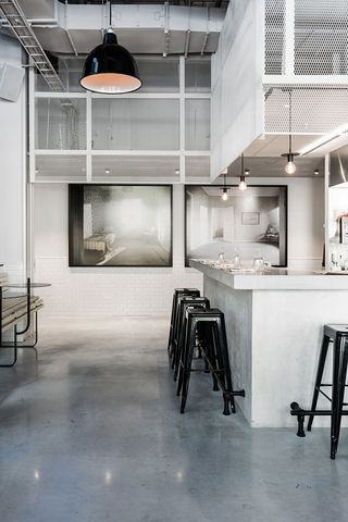 A counter and three black stools sit on a polished concrete floor
