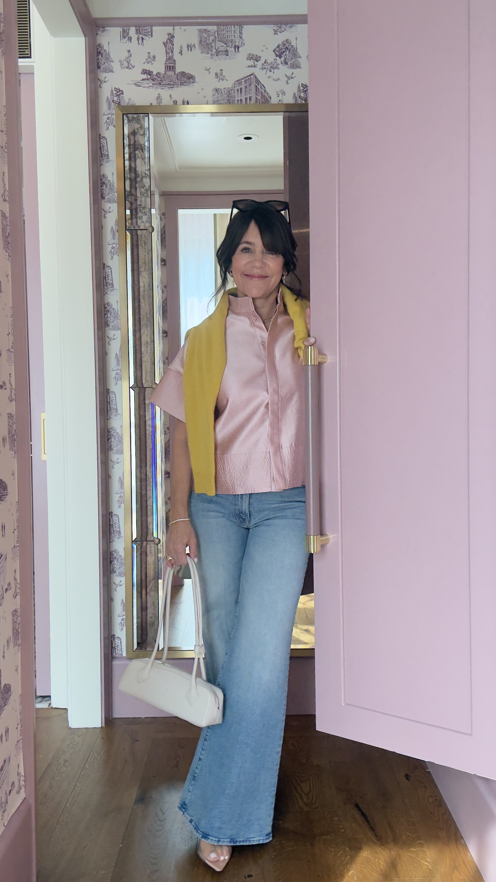 A former Nordstrom buyer wearing a pink silk top, a yellow scarf, and light-wash jeans.
