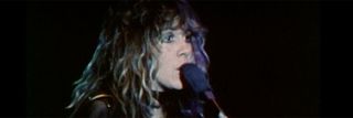 Stevie Nicks singing into the microphone while playing with Fleetwood Mac.