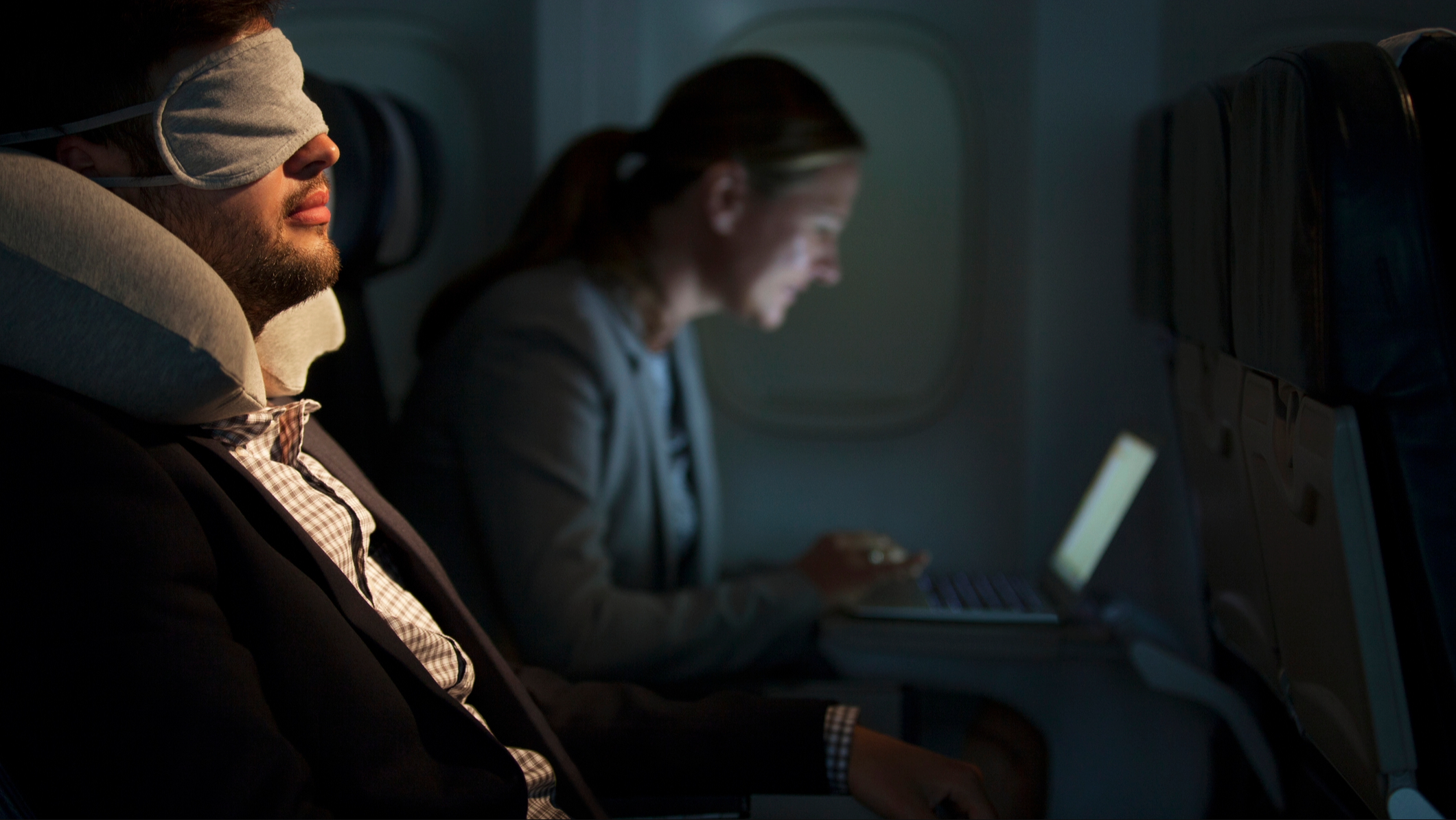 A man sleeping on a plane to avoid jet lag
