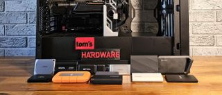 Recent extneral SSDs in front of our storage testbed, with 3D-printed Tom's Hardware logo