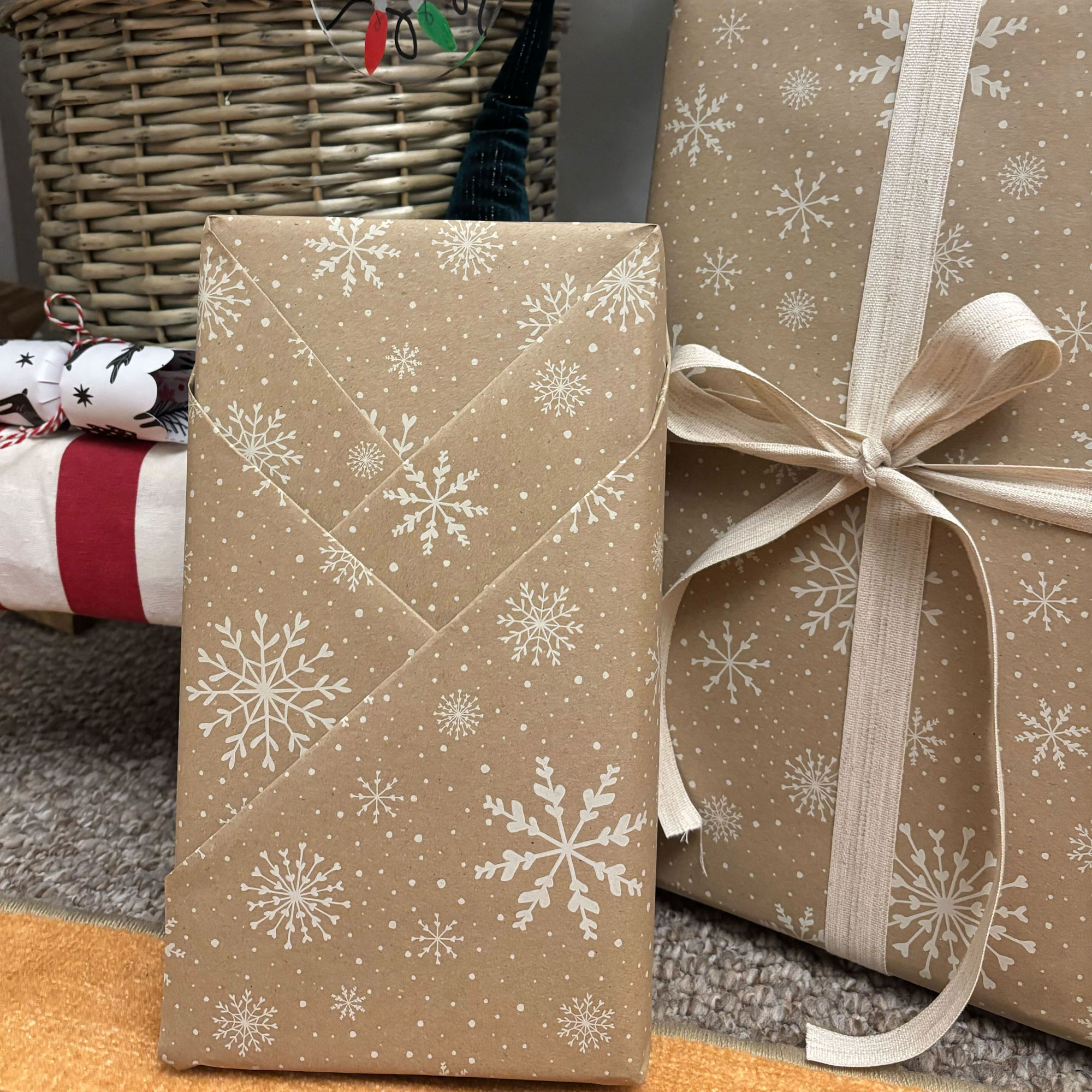 A rectangular box wrapped in brown paper with a white snowflake print on it