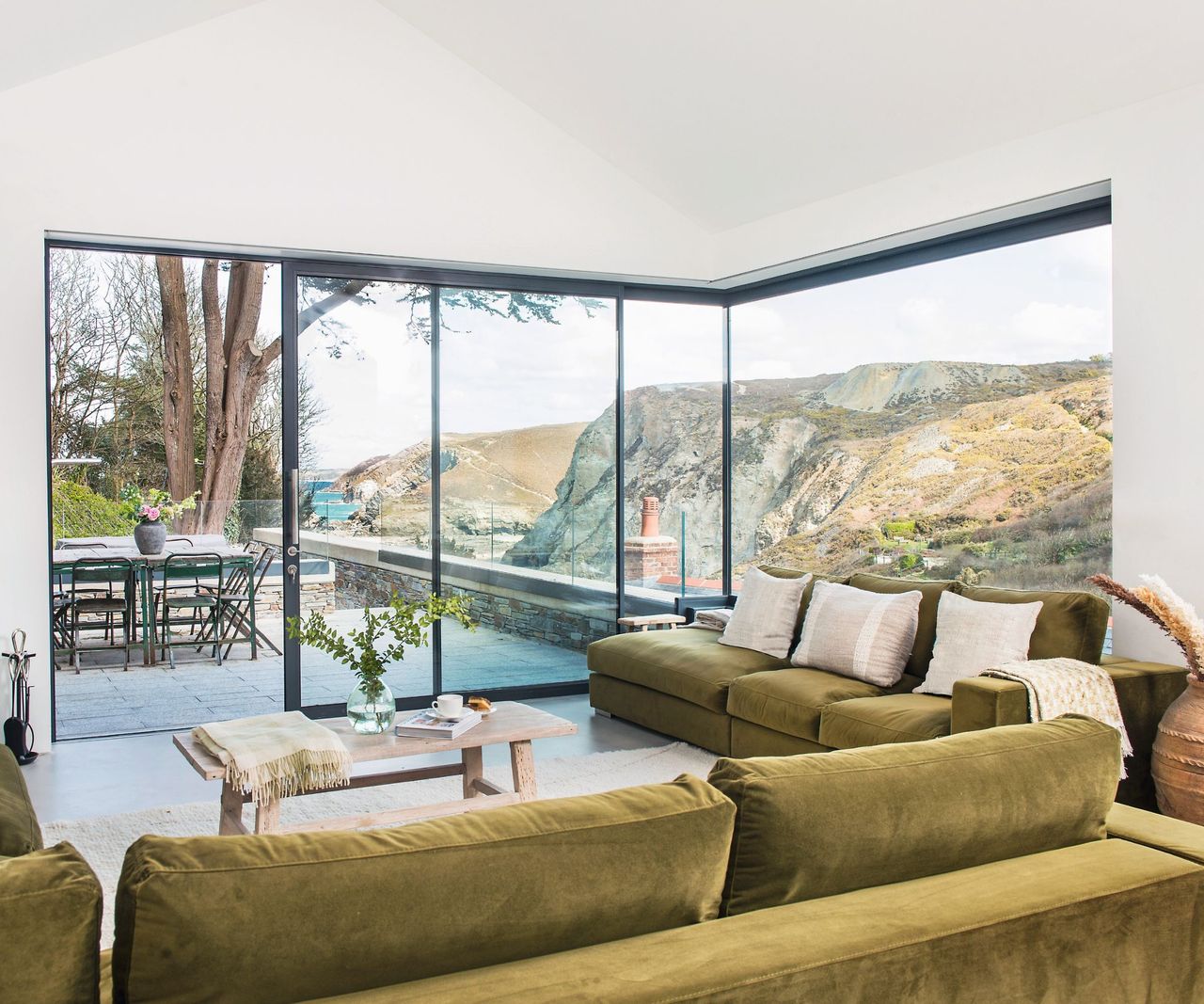 Green velvet sofa, black framed glass doors, wooden table