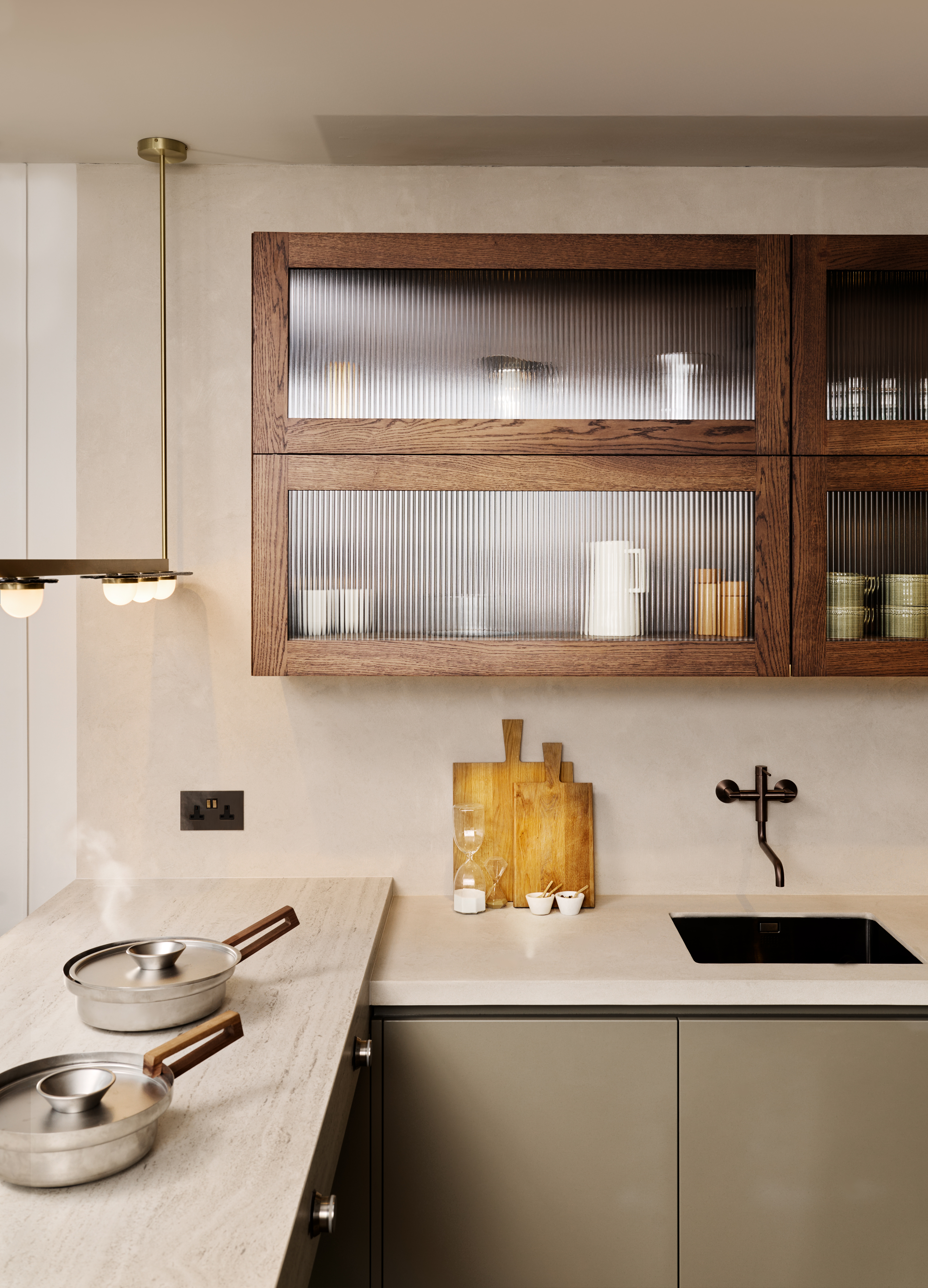 invisible worktop in a small luxury kitchen with travertine-look counters and green cabinets