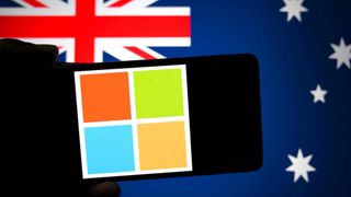 A Microsoft logo is seen displayed on a smartphone with a flag of Australia in the background.