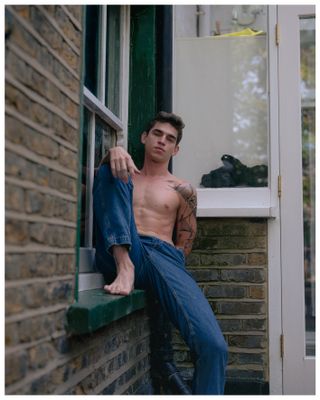 Male model sitting on a wall outside