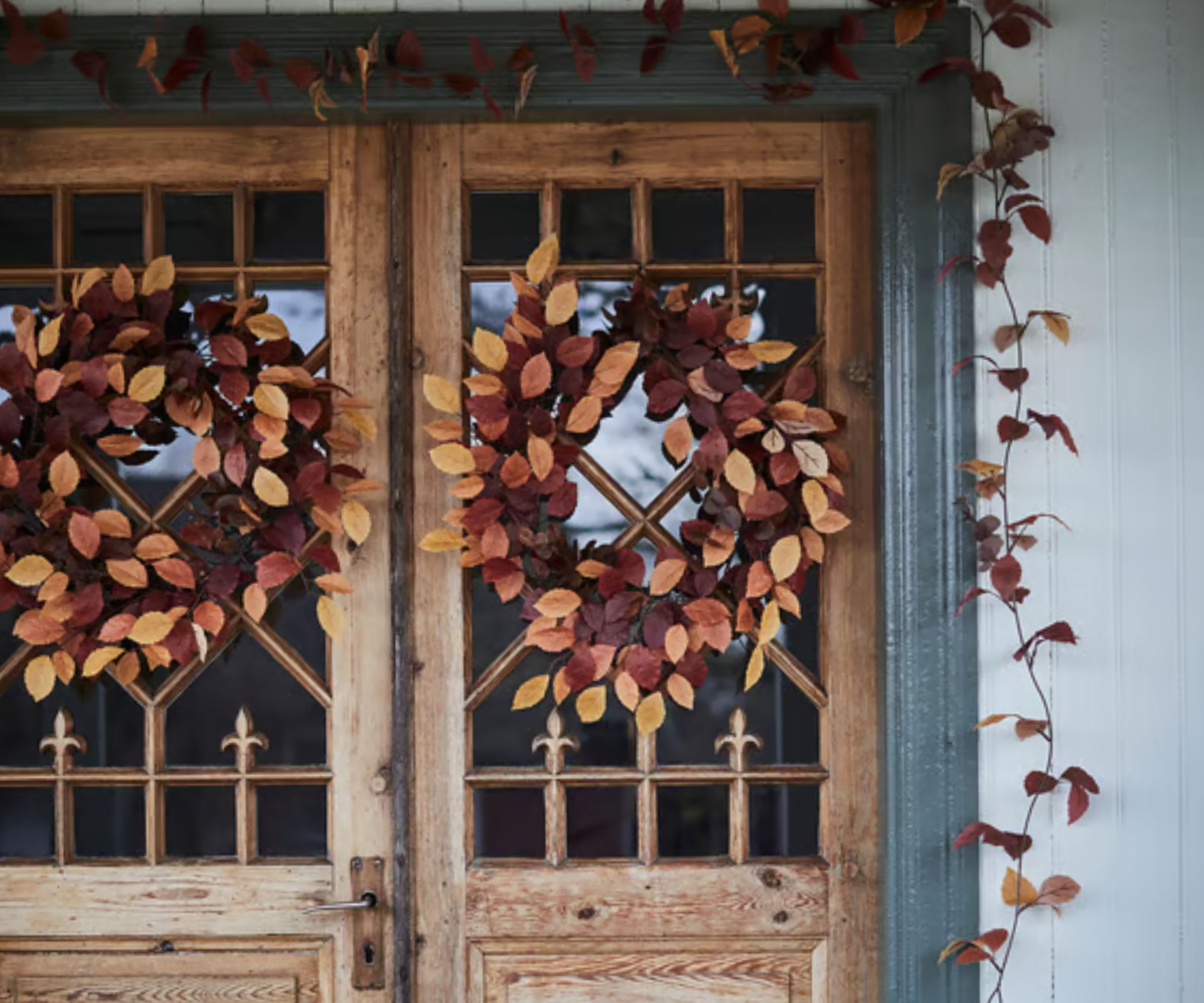 Wood front door with glass panes and autumnal leaf wreath and garland