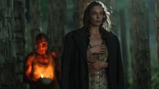 Jodie Comer walks ahead of a fire lit Ralph Fiennes in 28 Years Later.