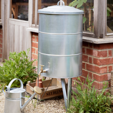 Garden Trading galvanised steel water butt by a greenhouse 
