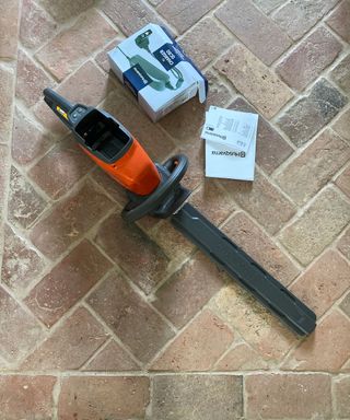 Husqvarna 115iHD45 cordless hedge trimmer on the floor inside a house