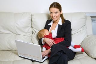 A woman breastfeeds while on a laptop.
