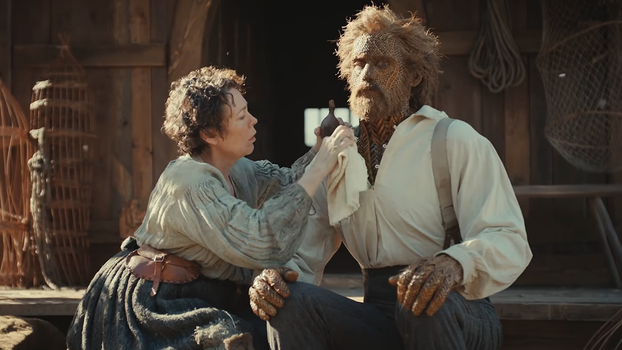Olivia Colman leaning in to fix something on Alexander Skarsgard in Wicker