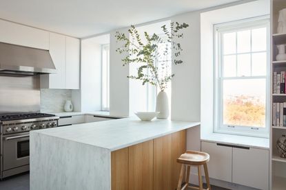 A white kitchen with stainless steel, marble and wood