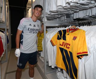 Arsenal midfielder Charlie Patino poses alongside an old Gunners shirt at the Adidas campus during pre-season in July 2022.