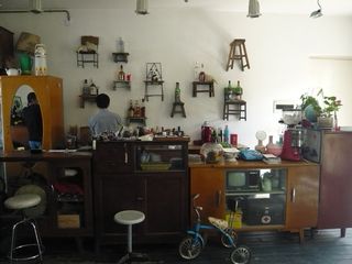A variety of old chairs and stools are attached to a wall behind a row of vintage cupboards