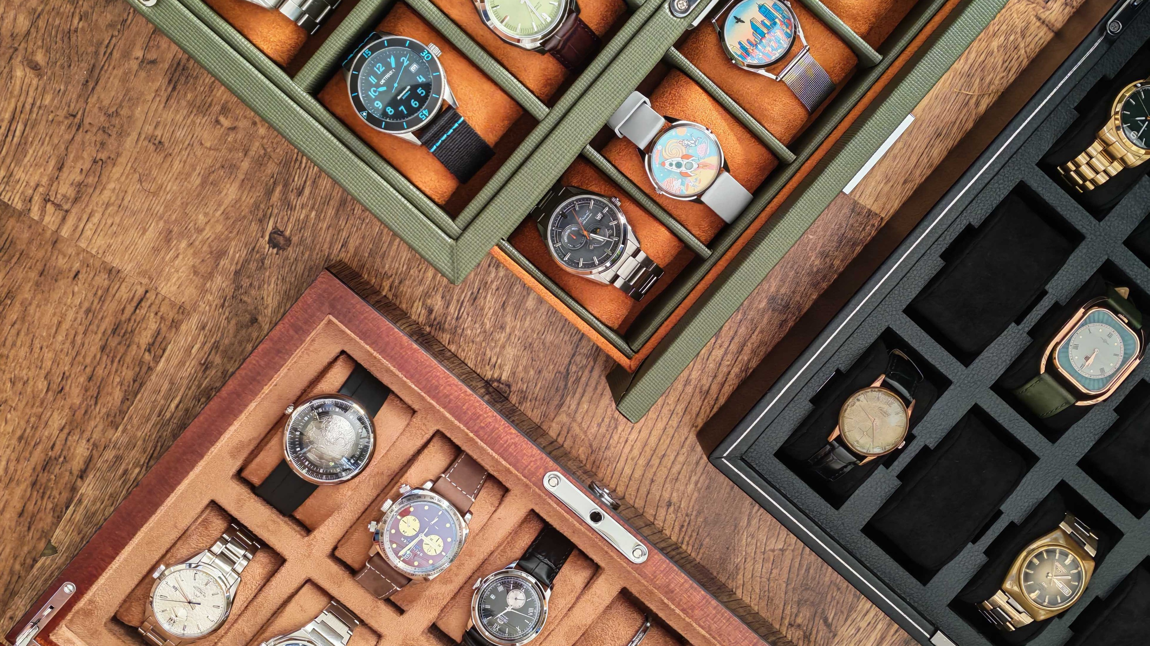 Best watch box – three watch boxes part-filled with watches of various brands.