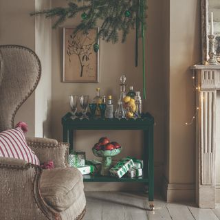 A scalloped drinks trolley with cocktail essentials and Christmas presents with a large armchair next to it