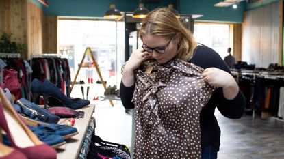 Woman holding brown and cream spotted top against her body 