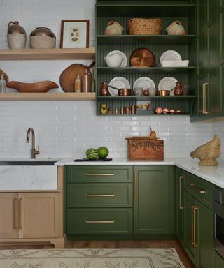 green and wood kitchen with open shelving and wal cabinet, white metro tiles, marble countertops, rug,