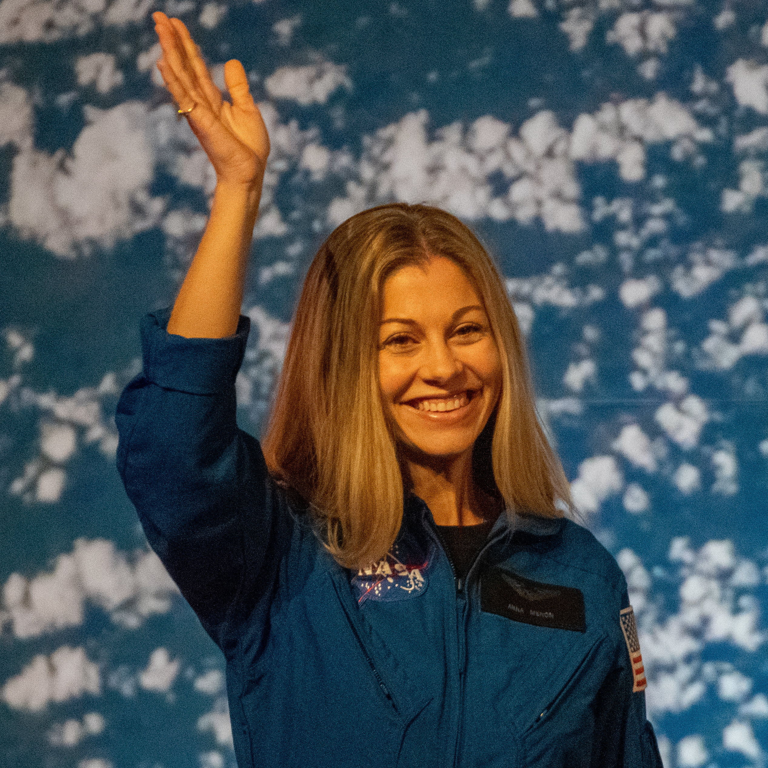 people in blue jumpsuits smile and wave.