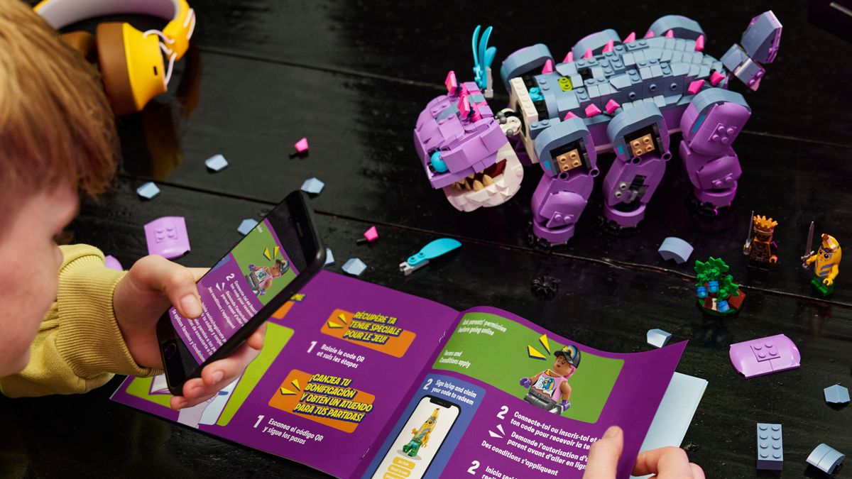 A person looks at the instructions for Lego Klombo while the model and minifigures can be seen amongst pieces on a table