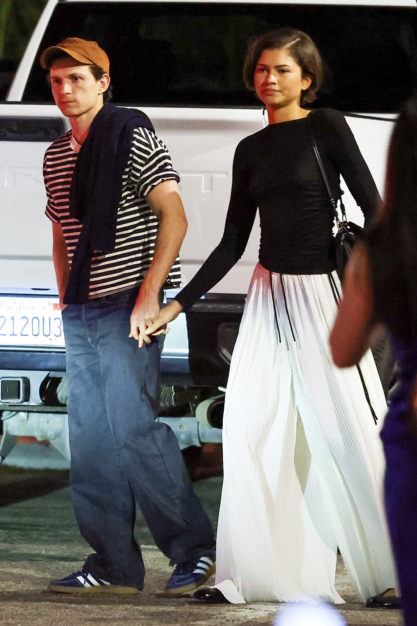 Tom Holland with Zendaya wearing a black top, white billowy pants, and black shoes