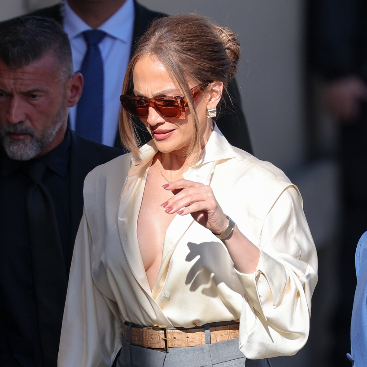 Jennifer Lopez wearing a white satin button-down blouse with wide-leg trousers and platform shoes, arriving at Jimmy Kimmel Live in Los Angeles