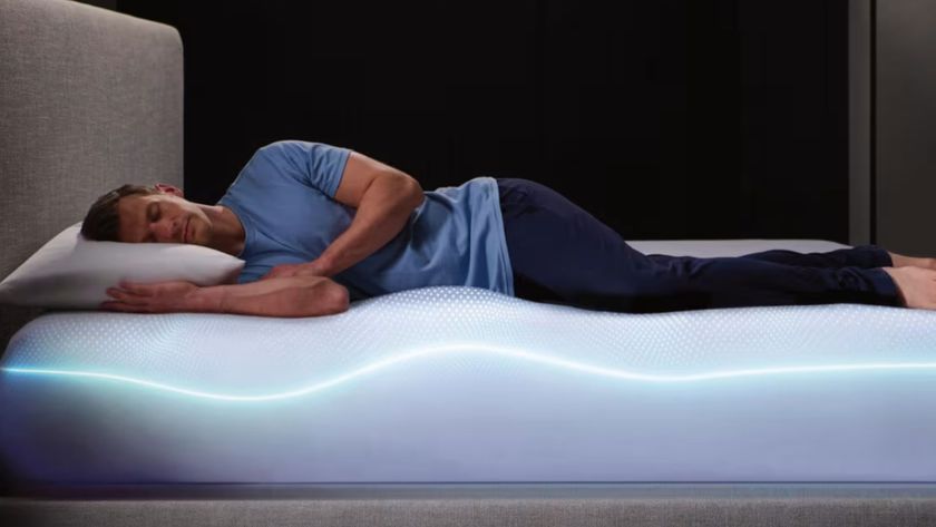 A man in blue pyjamas laying on his side on Sleep Number Climate360 smart mattress 