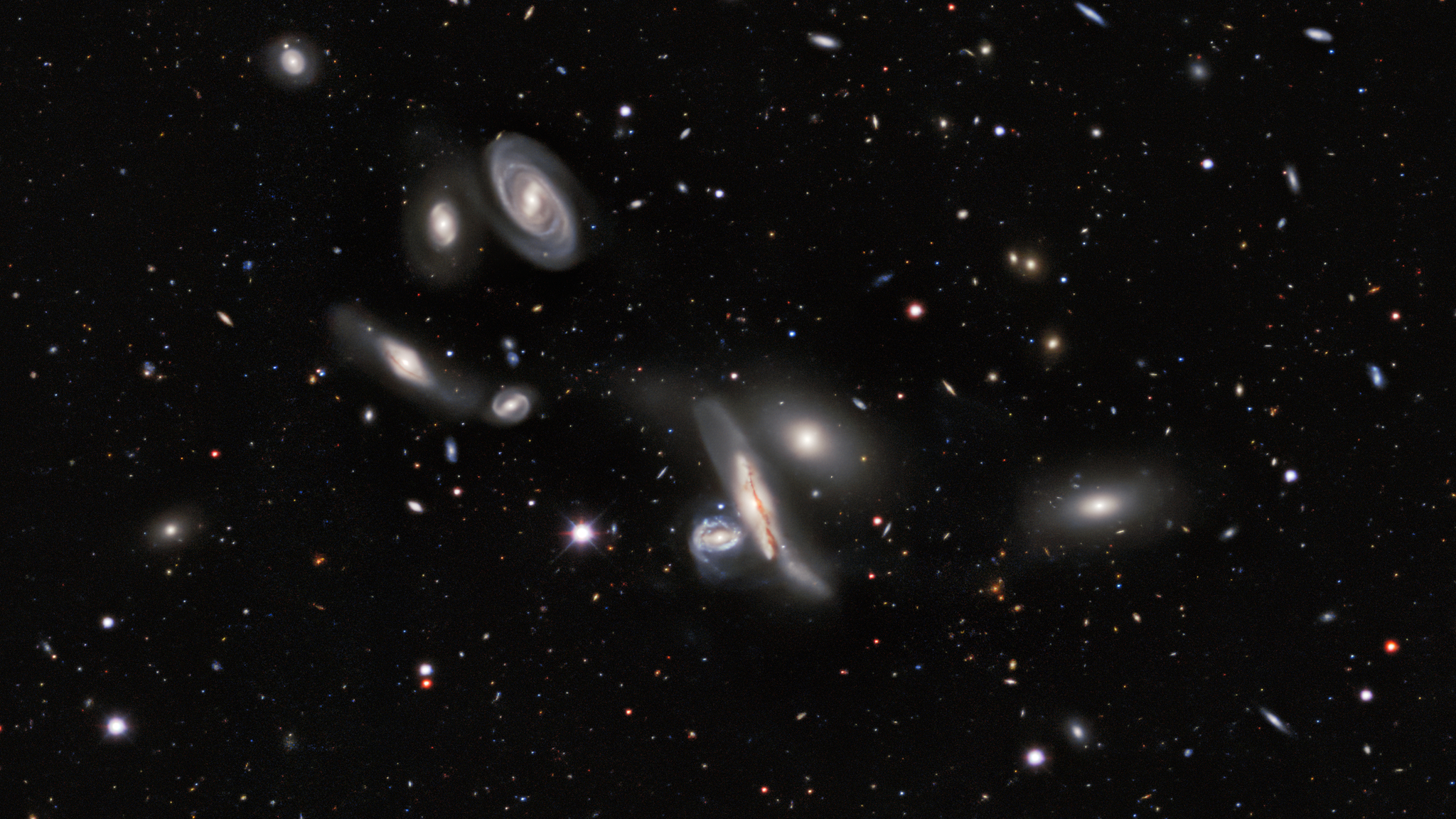 A deep space image showing a series of swirling galaxies in the darkness of space