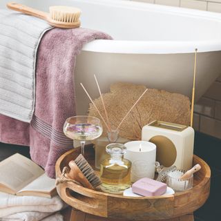 A bathroom with a free-standing bath and a self-care tray next to it with a lit scented candle