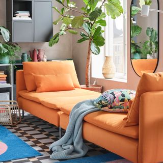 living room with orange sofa, checked floor tiles, wall units, storage space, plants, large plant behind sofa