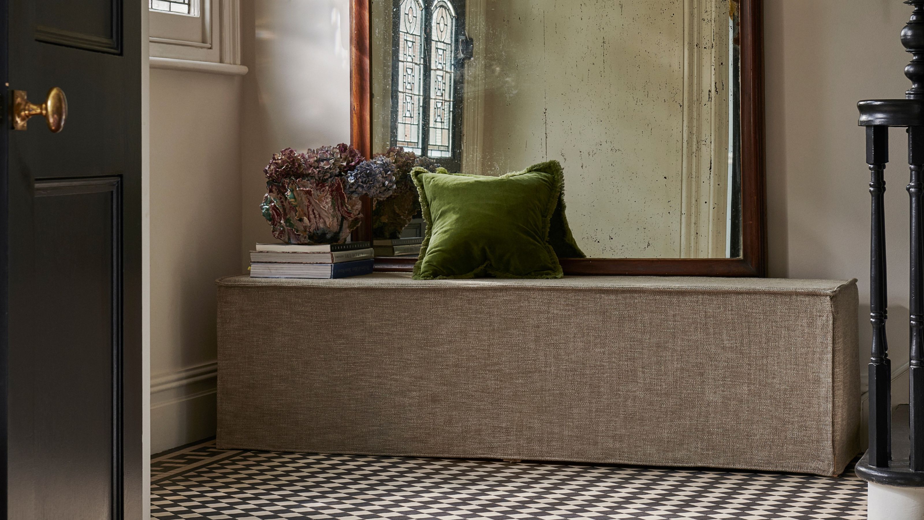 Sofa.com Anders Bench in entryway with mirror, cushion, books stacked up, and flowers in vase, with black and white heritage tile floor