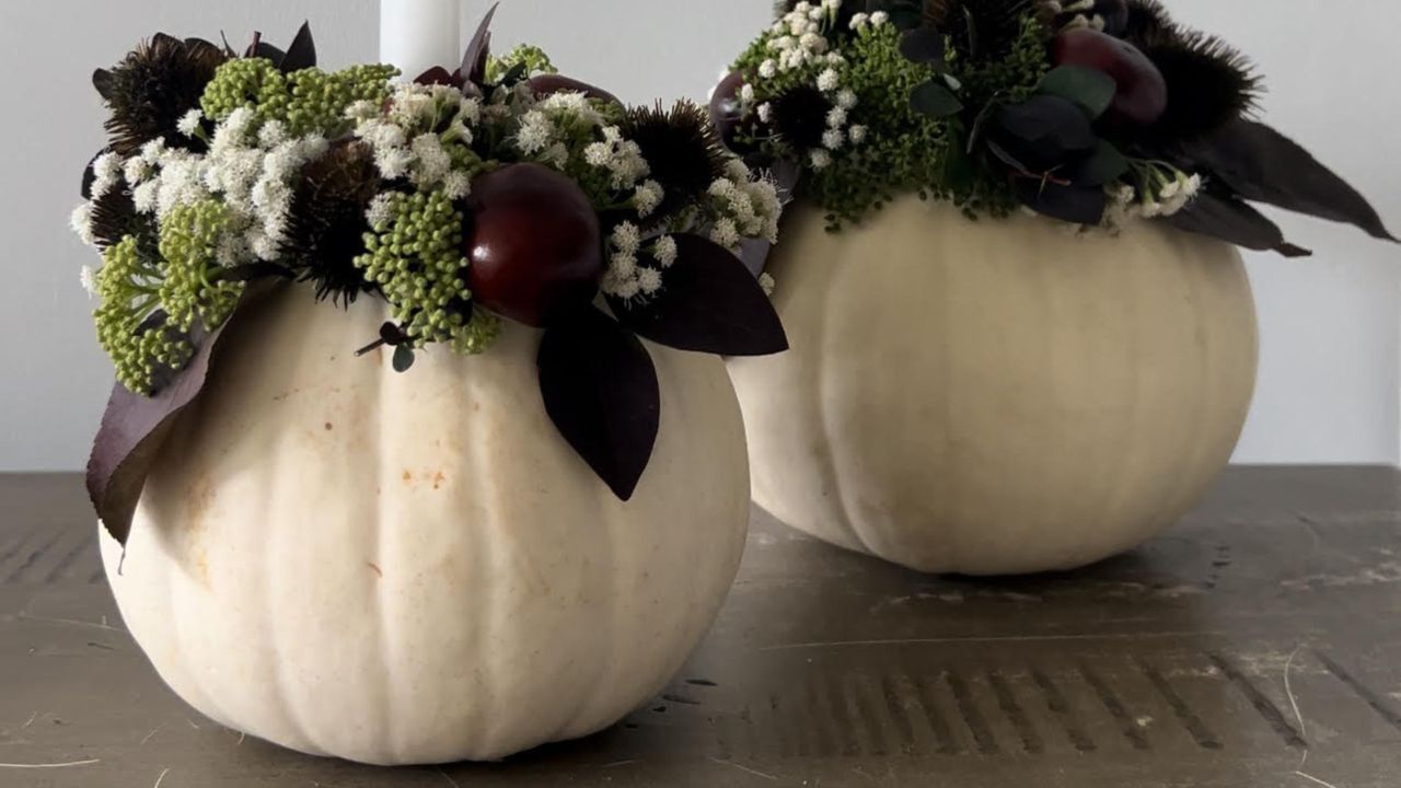 two white pumpkins with dark flowers adorning them