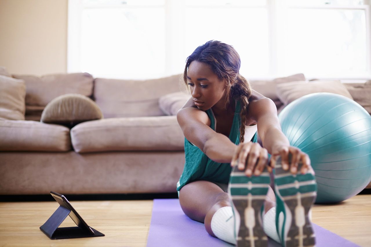 Exercise protects you against COVID: A woman stretching out after working out in her living room