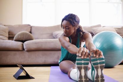 Exercise protects you against COVID: A woman stretching out after working out in her living room