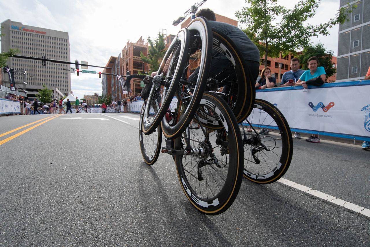 A mechanic brings wheels to the pit for the criterium