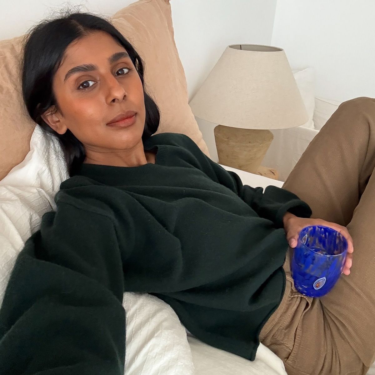 Monikh wears a green sweater and beige jeans.