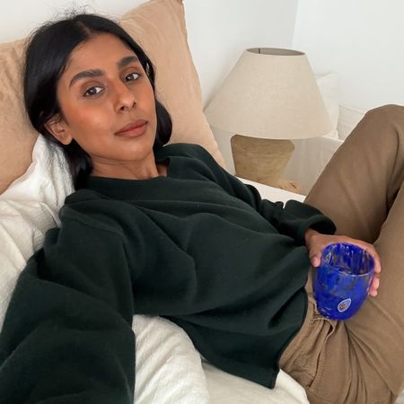 Monikh wears a green sweater and beige jeans.